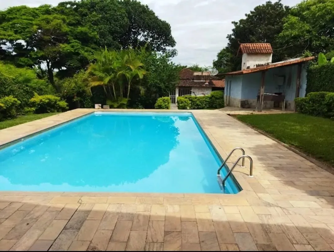 Piscina da unidade em area aberta, cercada por gramado e arvores.